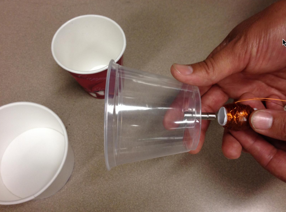 Holding the solenoid next to the permanent magnetics attached to each side of the bottom of the cup